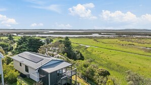 Een modern huis met een zonnepaneel dak, omringd door weelderige begroeiing en uitzicht op een rivier.