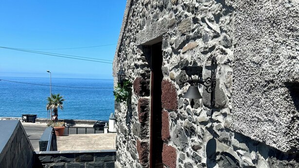Um edifício de pedra com telhado de cerâmica com vista para o mar.