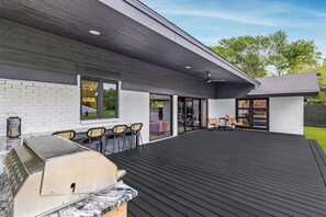Ulkoterassi, jossa on grilli, oleskelualue ja katettu patio.