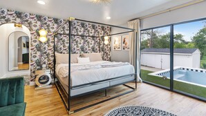 Un dormitorio con cama con dosel, un ventanal con vistas a una piscina y un espejo con luces.
