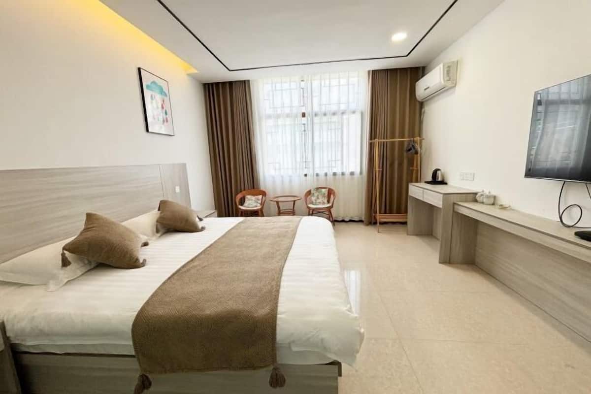 Una habitación de hotel con una cama grande, un escritorio, una silla y un televisor.
