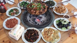 Una mesa redonda con varios platos, incluyendo un caldo caliente, comida frita y una variedad de acompañamientos.