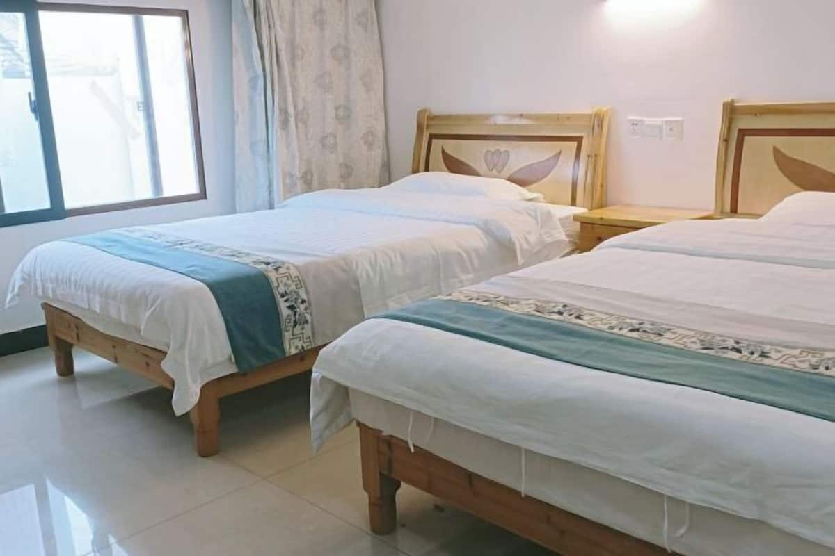 Una habitación con dos camas de madera, una ventana con cortinas y suelo de baldosas.