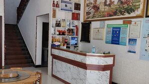 Una recepción con diseño de mármol, una escalera y un comedor con sillas de madera.