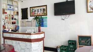 Zona de recepción con mostrador de mármol, certificados enmarcados, televisor y una pizarra.