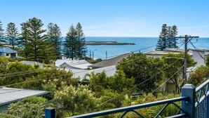 A coastal residential area with houses, a pier, and a clear view of the sea.