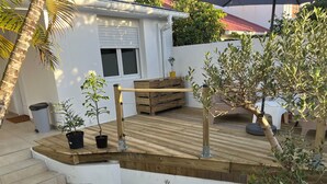 Eine Holzterrasse mit Blumentöpfen, einer Bank und einem kleinen Tisch.
