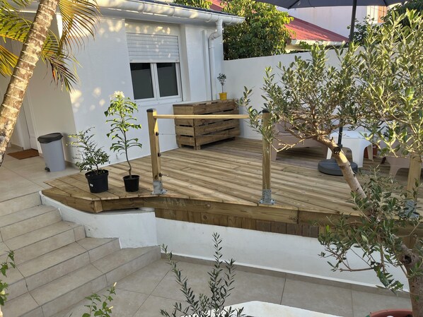 A wooden deck with potted plants, a bench, and a small table. - Chambre Studio Confort, Plein Centre, Accès Piscine, Idéal Pour Couple (Baie-Mahault)