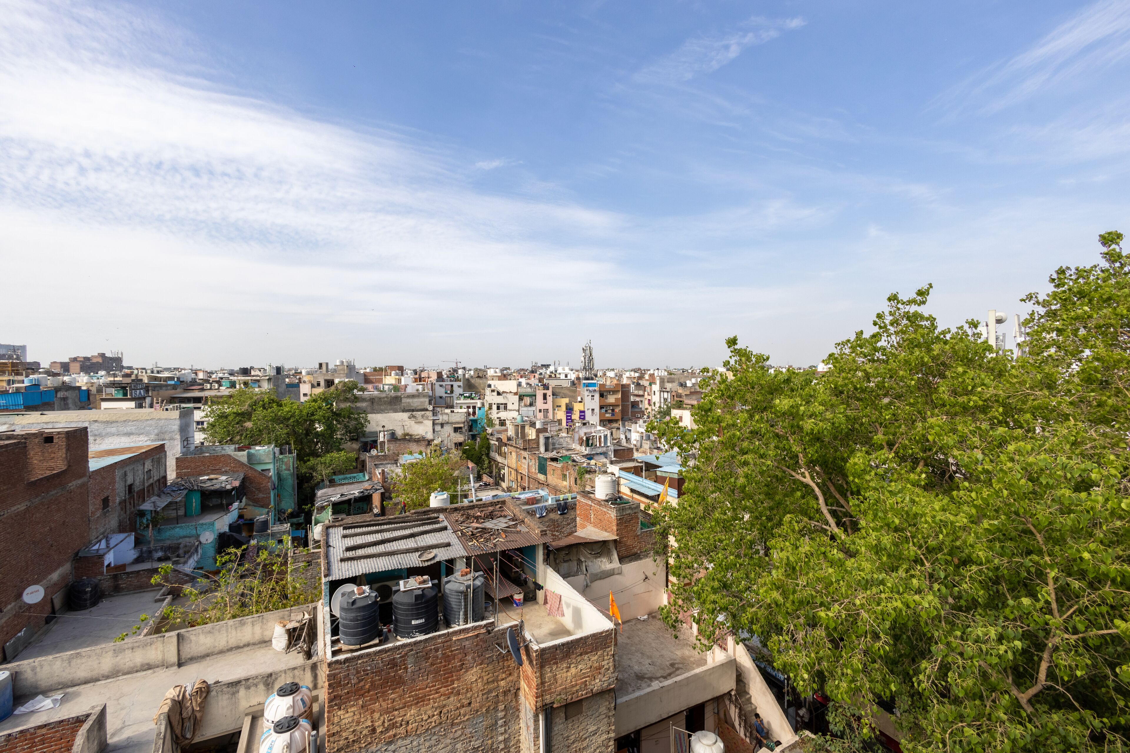 A densely packed urban area with multi-story buildings, some with visible water tanks on rooftops, and a clear sky.