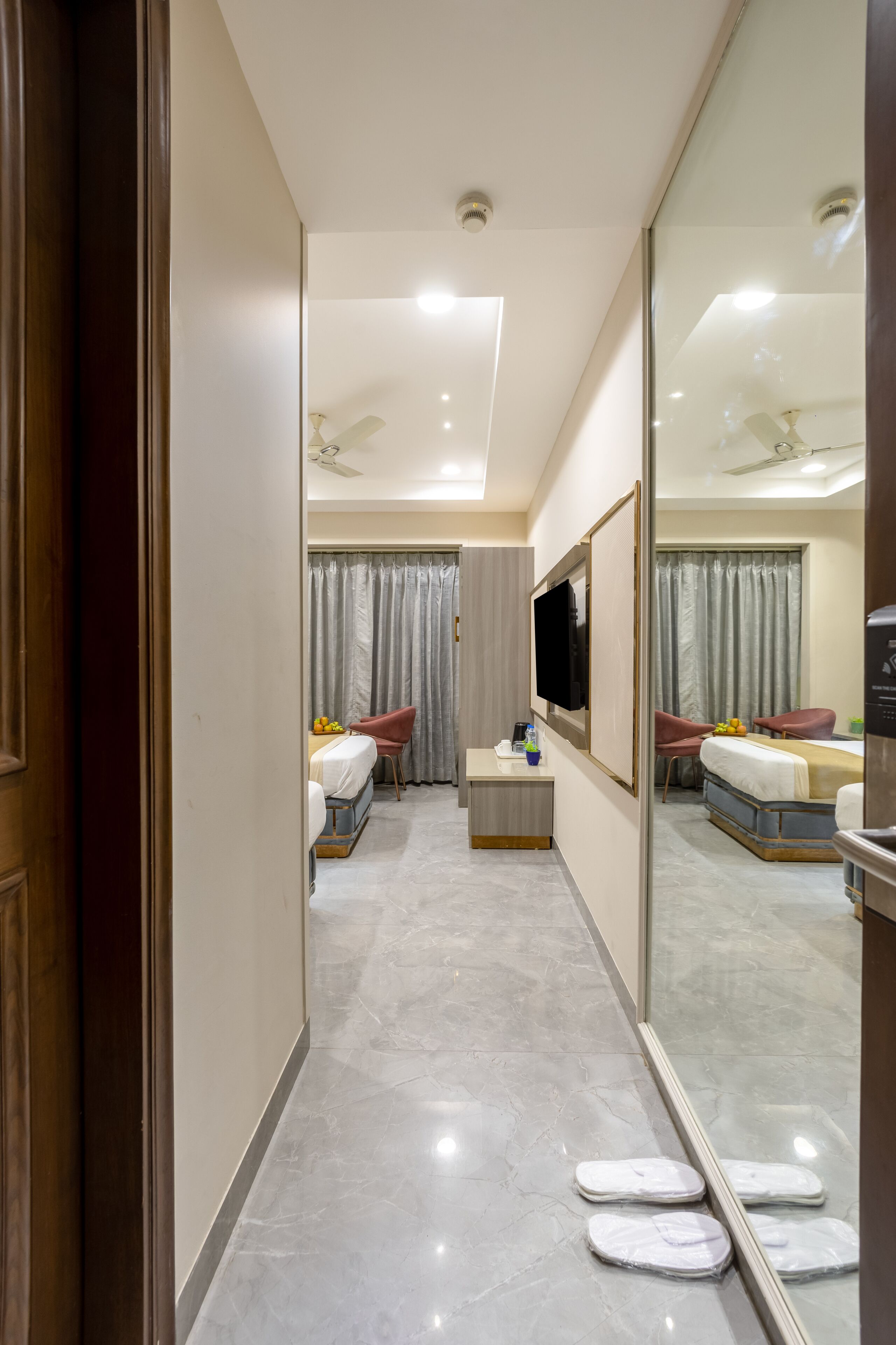 A hotel room with a bed, a TV, a desk, a chair, a mirror, and a bathroom with a shower and toilet.
