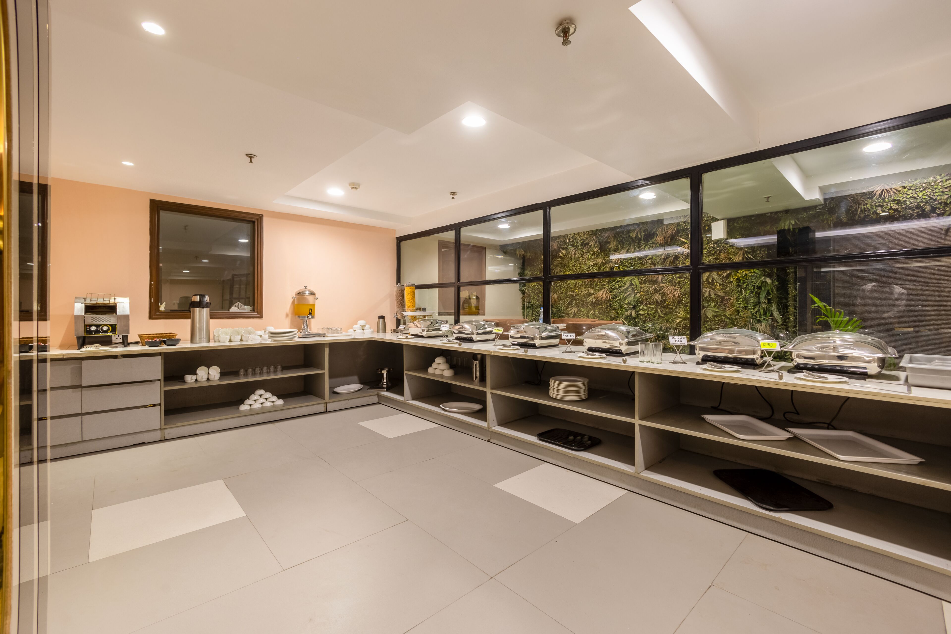Une cuisine moderne dotée d’un long comptoir, d’appareils électroménagers intégrés et d’une grande fenêtre offrant une vue sur la verdure.