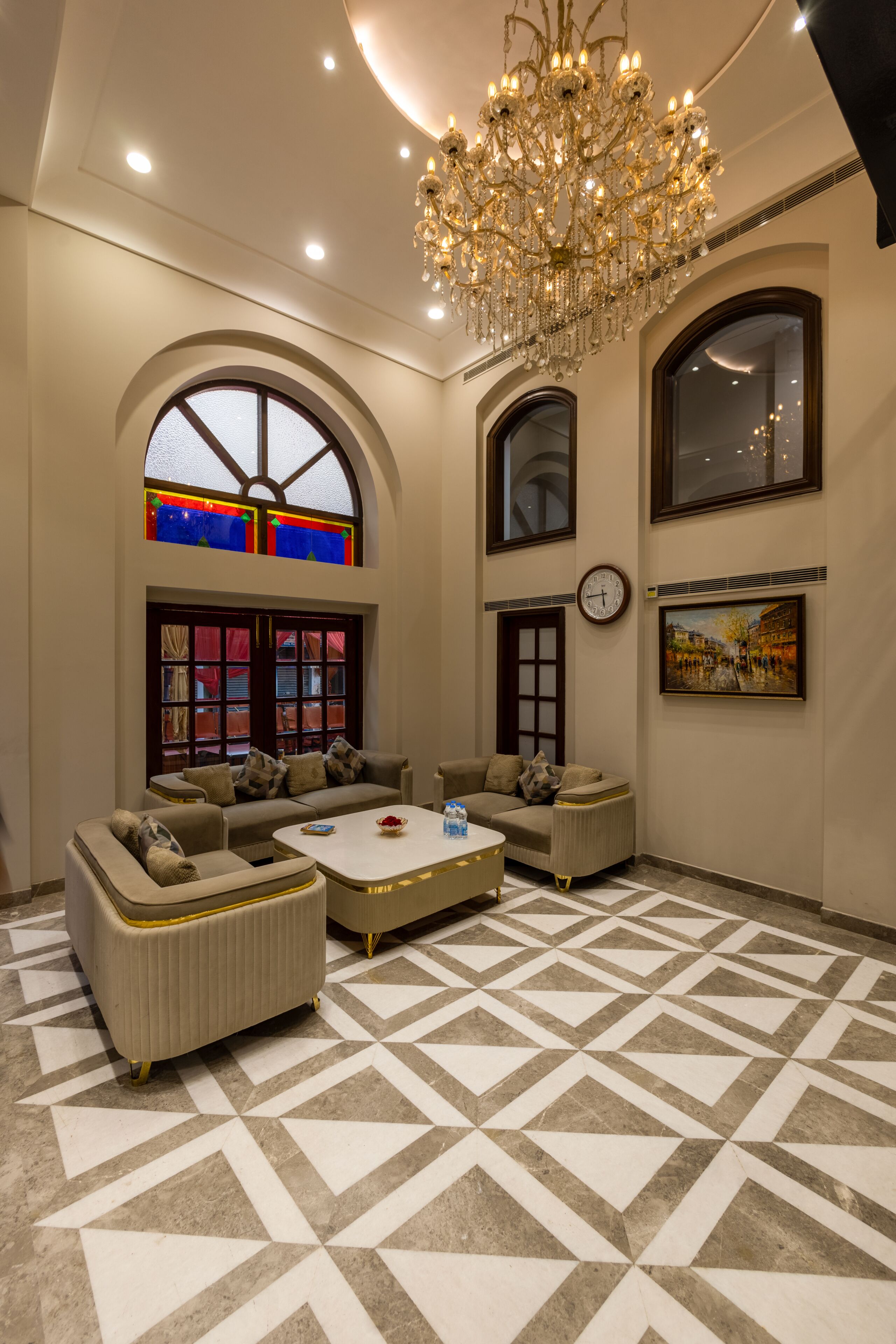 A spacious living area with a chandelier, sofas, a coffee table, and a patterned floor.
