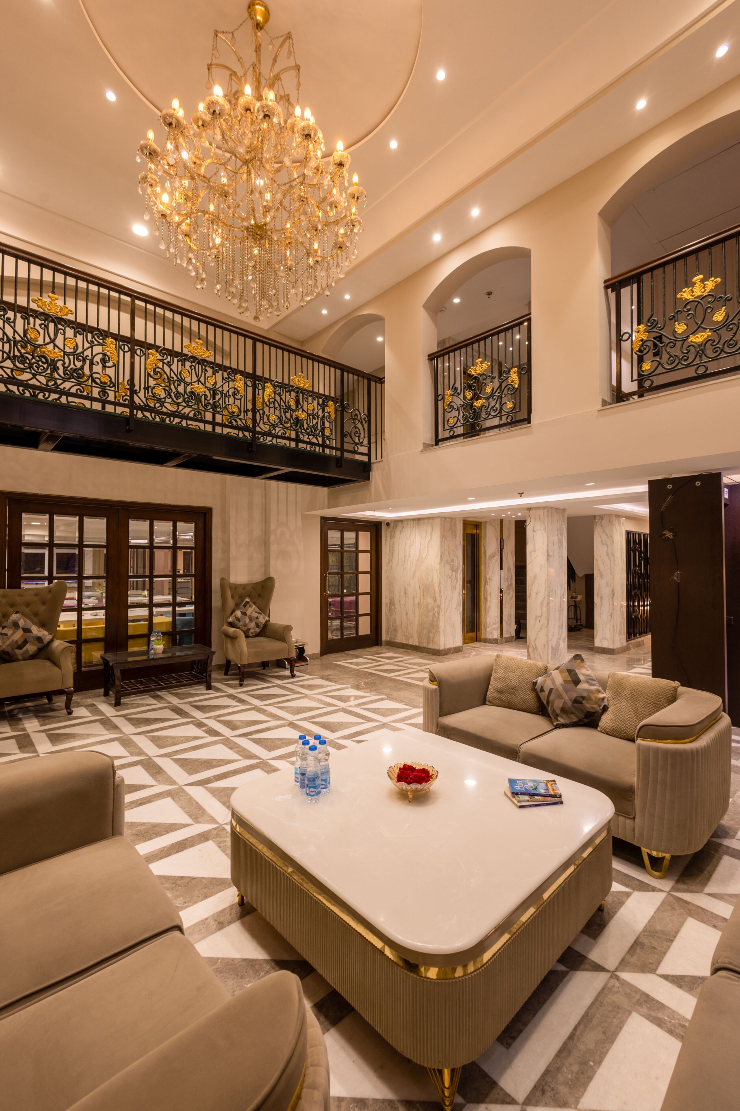 A spacious lobby with a chandelier, a high ceiling, and a checkered floor.
