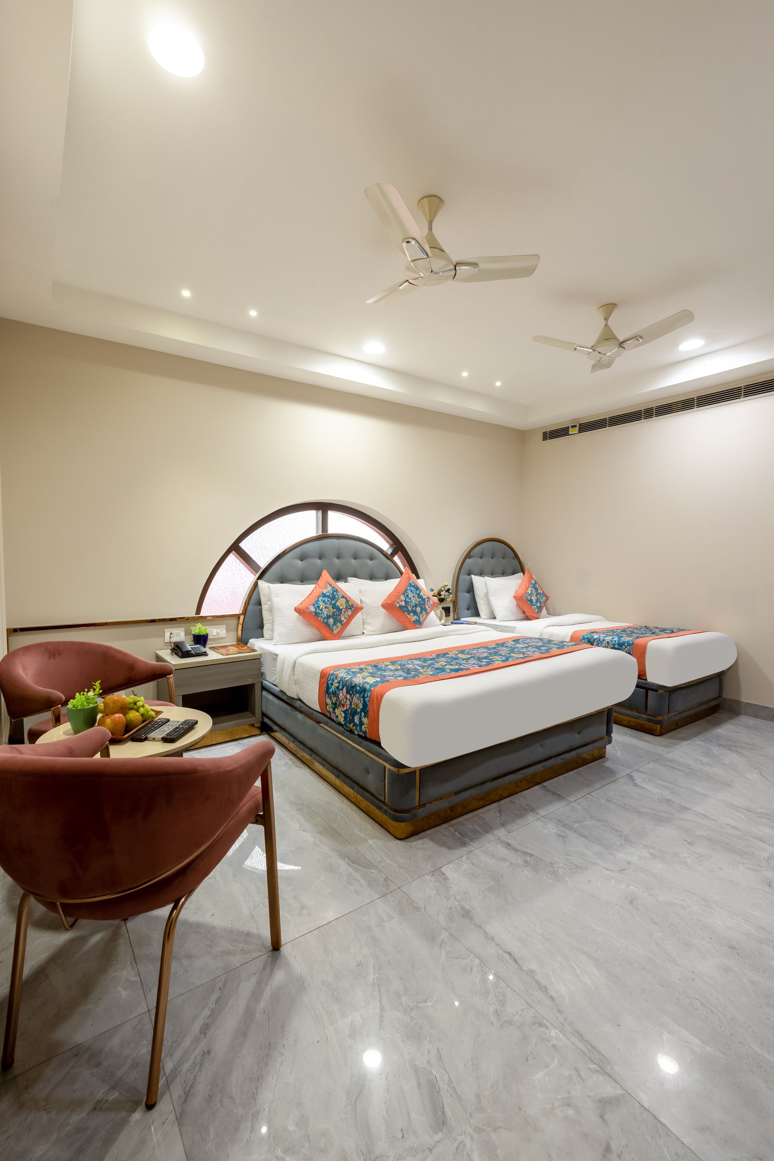 A hotel room with a bed, two bedside tables, a chair, a desk, and a ceiling fan.