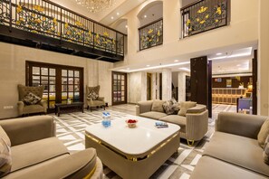 A spacious lobby with high ceilings, a balcony with ornate railings, and a checkered floor. - Hotel Sapphire House Paharganj (New Delhi)