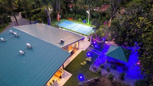 A residential property with a tennis court, a covered patio, and a landscaped garden.
