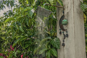 Un pommeau de douche fixé à un arbre, laissant l’eau couler.