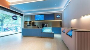 A modern reception area with a digital display, a coffee machine, and a seating area. - HanTing Hotel (Taizhou Sanmen) (Sanmen)