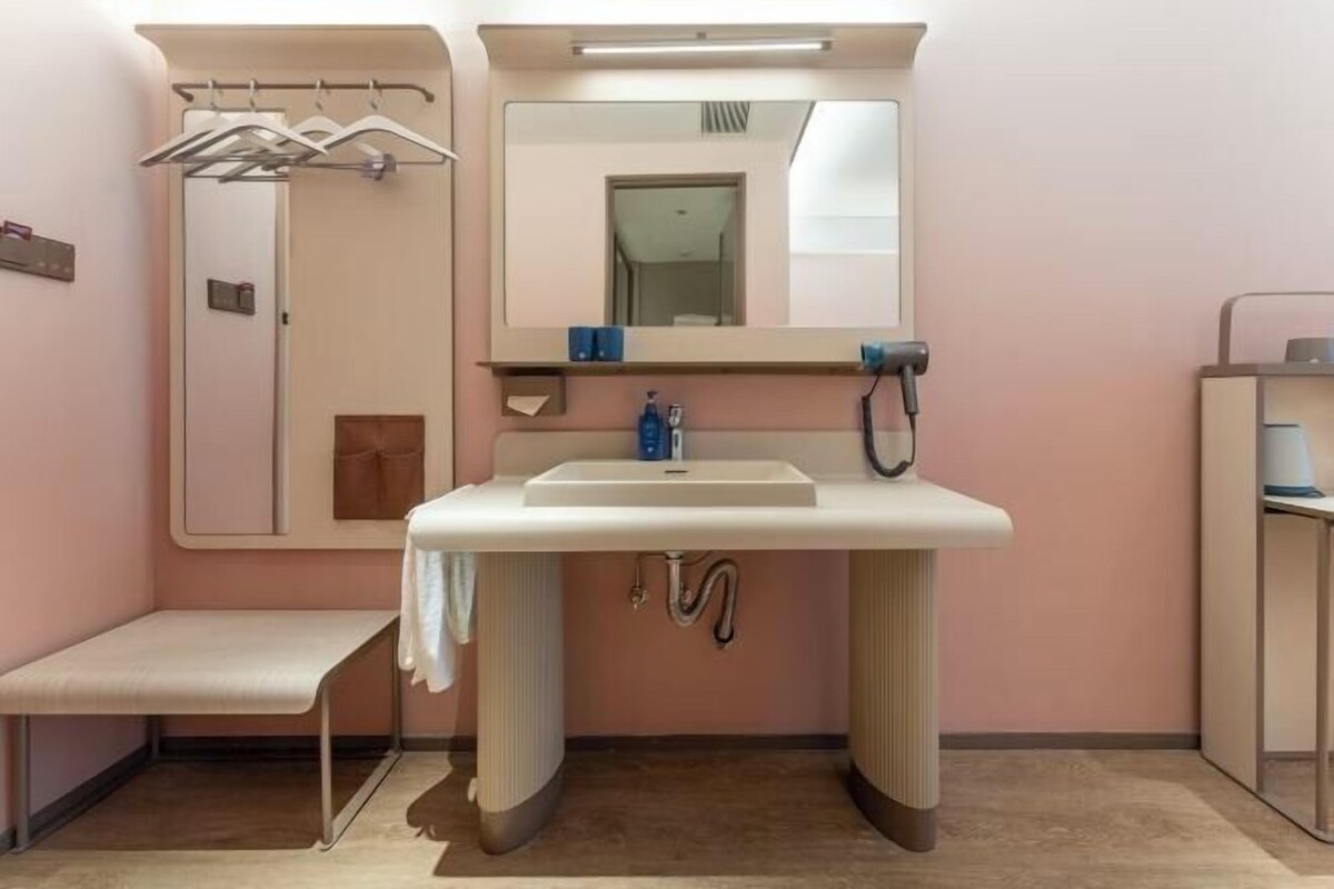 A bathroom with a sink, mirror, towel rack, bench, and a door leading to another room.