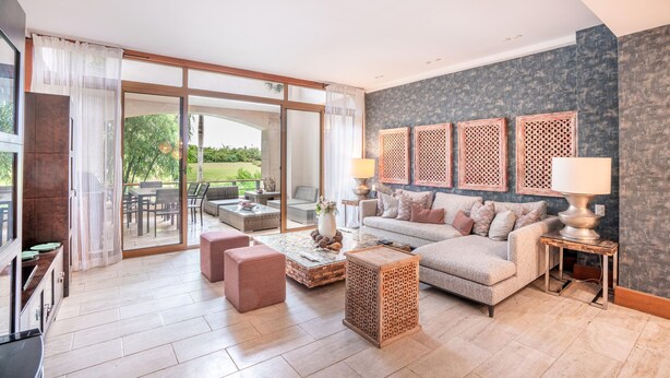 Een ruime woonkamer met een grote schuifpui naar een terras, een comfortabele bank, een salontafel en een televisie.