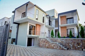 Stylish building with a modern design, featuring flat and sloped roofs, balconies, and a minimalist aesthetic.