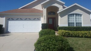 A single-story house with a garage, a front door, and a small porch. - 2551 Oneida Grantham (Kissimmee)