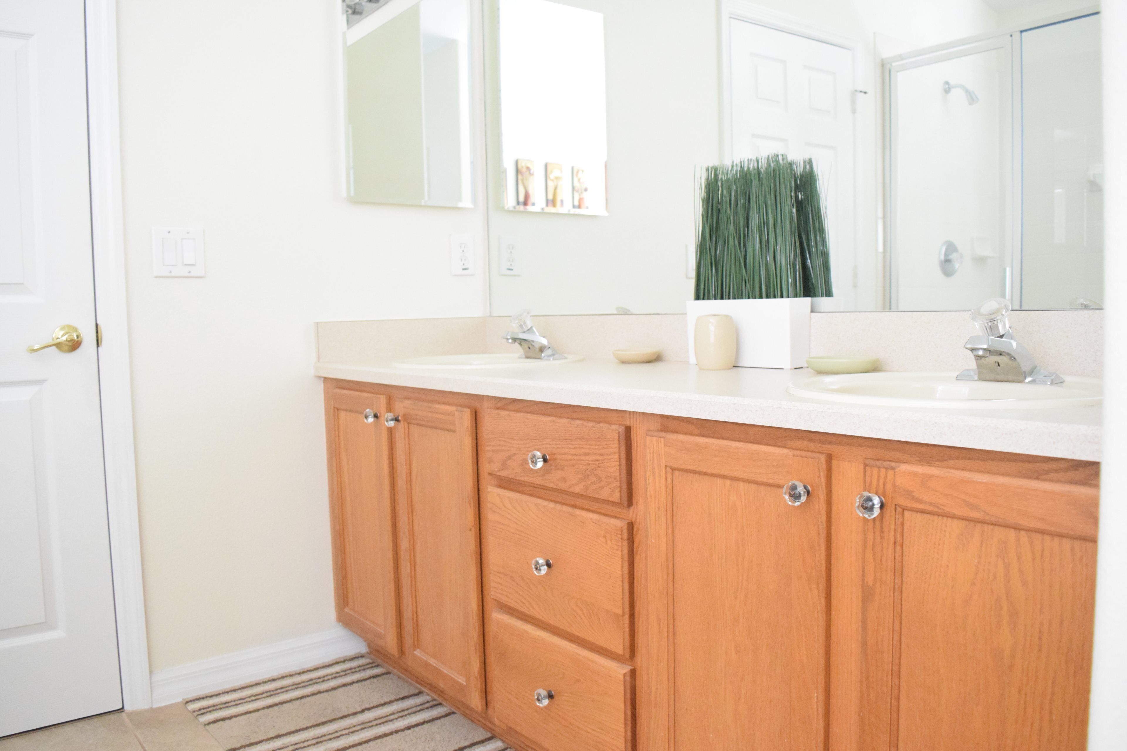 Un baño con armarios de madera, dos lavamanos y un espejo.