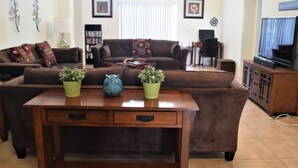 A living room with two sofas, a coffee table, a television, and decorative items. - 2551 Oneida Grantham (Kissimmee)