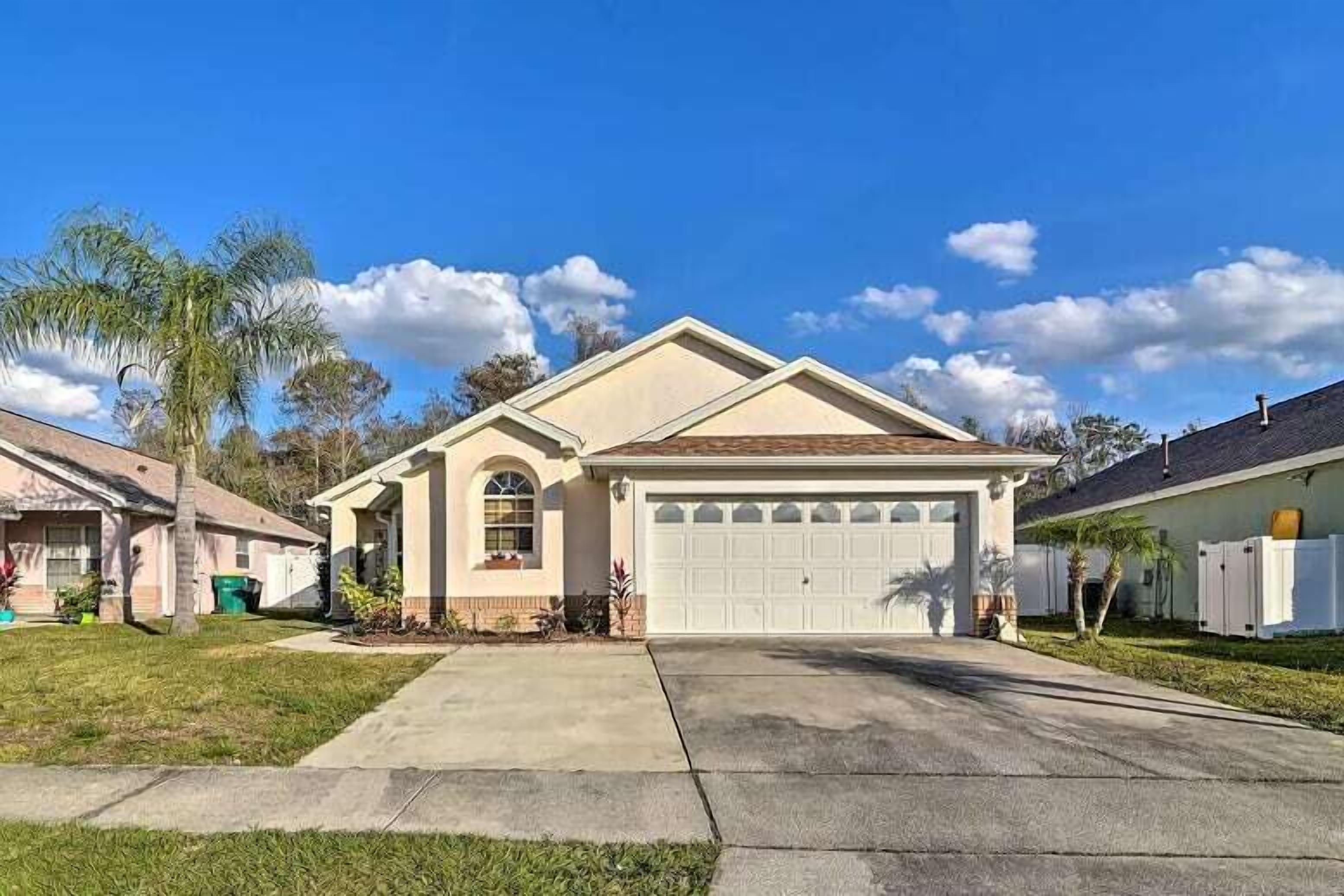 A single-story house with a garage, a front yard, and a clear blue sky.