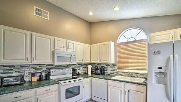 A modern kitchen with white cabinets, a microwave, stove, and a refrigerator. - 4 Bed Villa in Kissimmee, Orlando (Kissimmee)