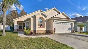 A single-story house with a garage, a front entrance, and a small front yard with plants. - 4 Bed Villa in Kissimmee, Orlando (Kissimmee)
