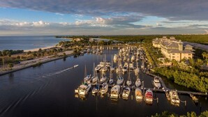 Un port de plaisance où sont amarrés de nombreux bateaux, entouré d’une zone de villégiature avec des bâtiments et de la végétation.