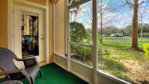 A room with a sliding glass door leading to a view of a road and trees.