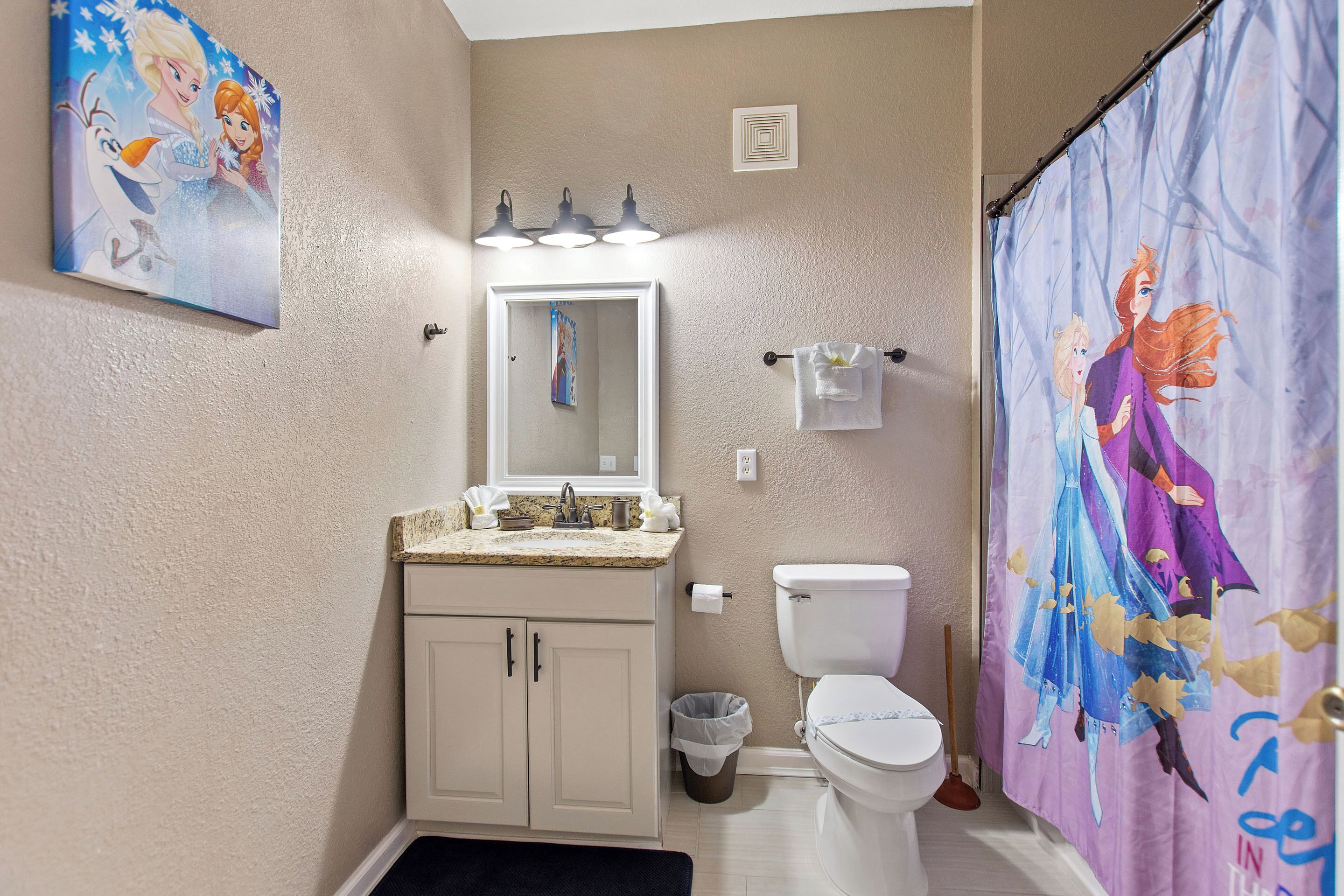 Un baño con inodoro, lavamanos, espejo y cortina de ducha.