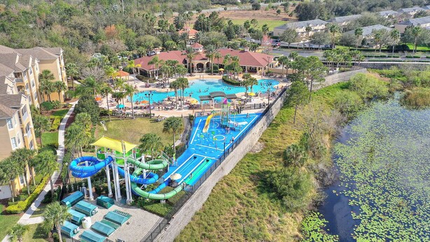 A resort with a large swimming pool, water slides, and a view of the surrounding landscape.