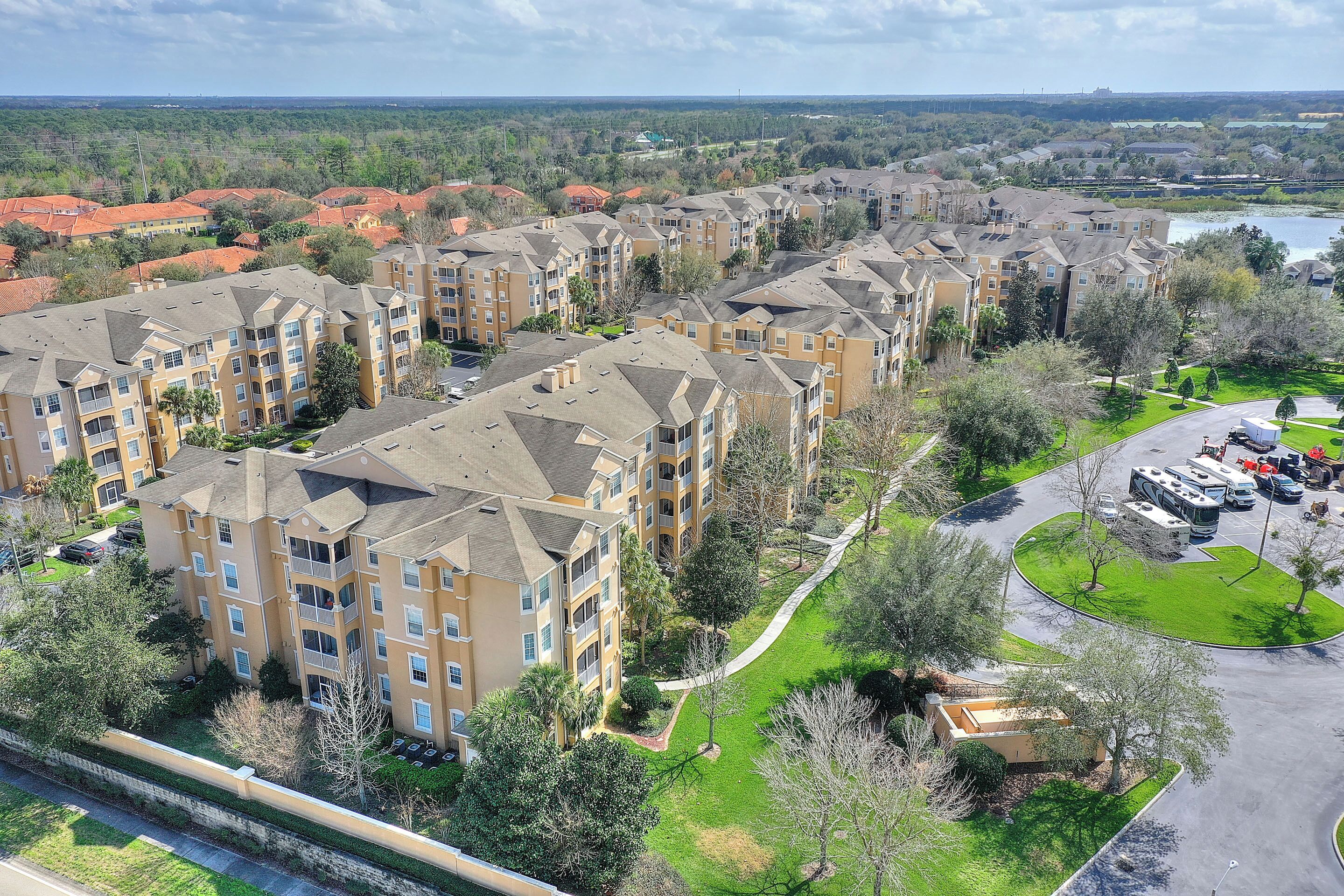 A residential complex with multiple apartment buildings, green spaces, and a parking area.