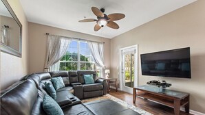 A living room with a sectional sofa, a TV, and a ceiling fan.