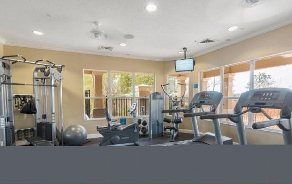A gym with cardio machines, weightlifting equipment, and a large exercise ball.