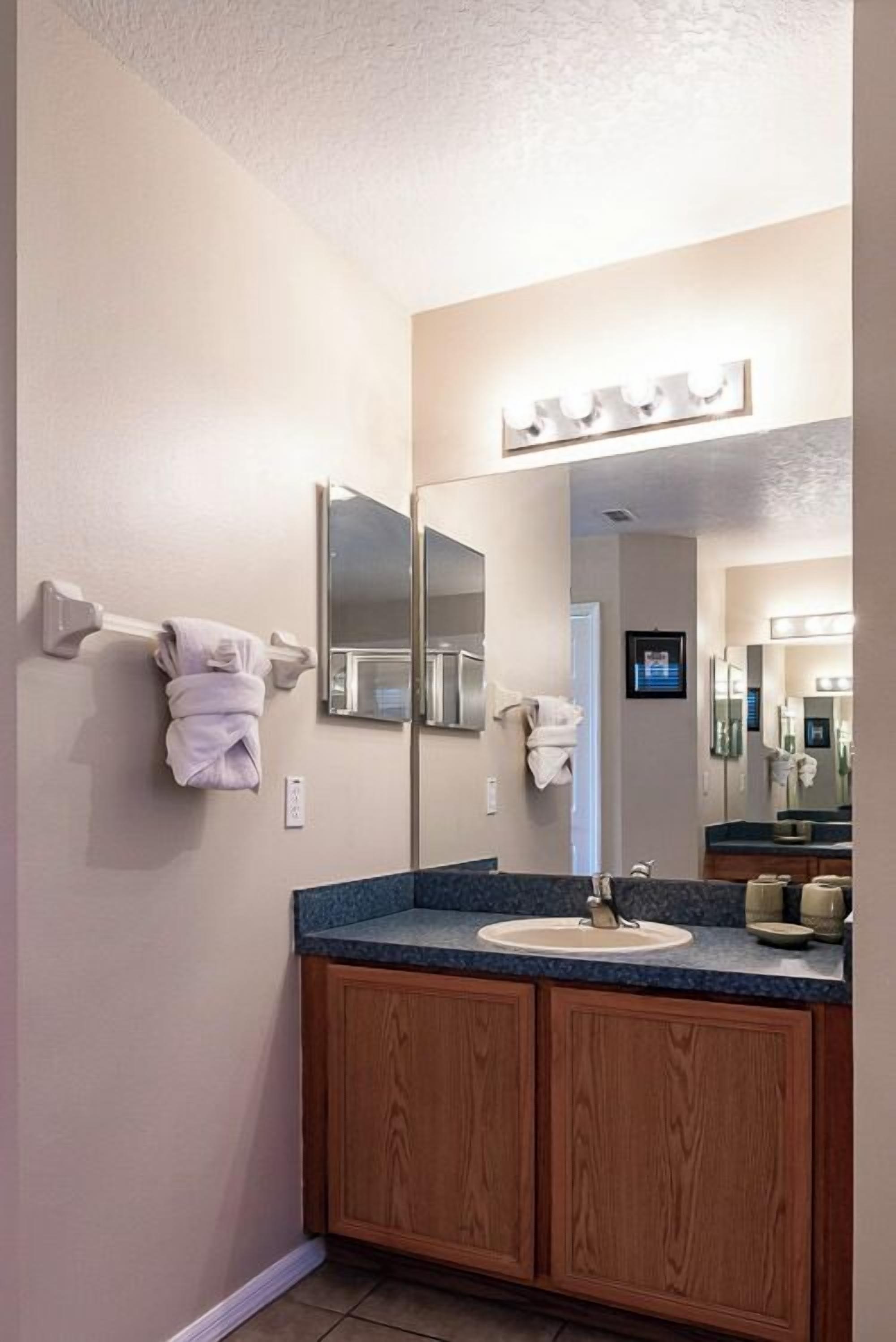 A bathroom with a sink, mirror, and towel rack.
