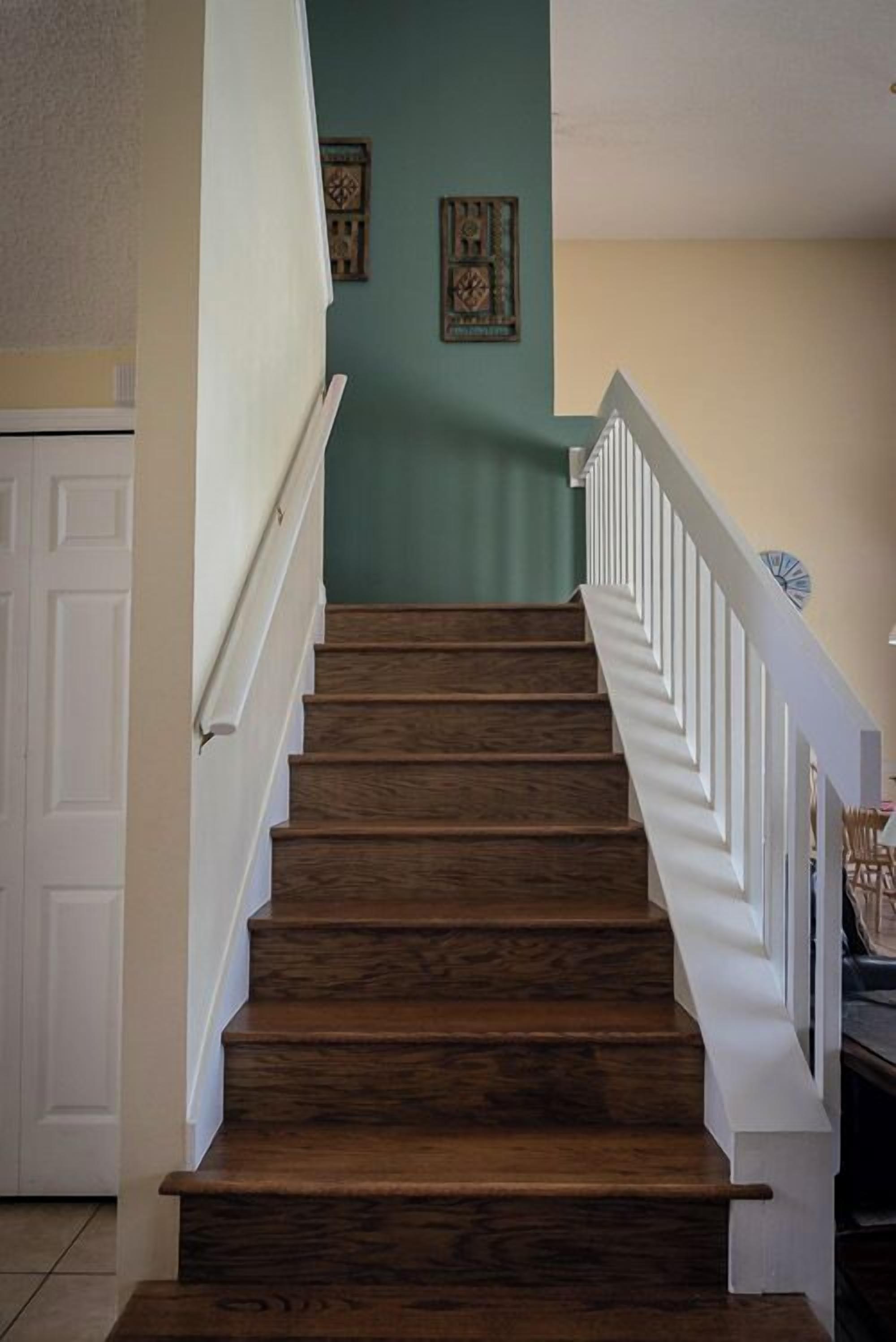 A wooden staircase with white railings leading to a landing.