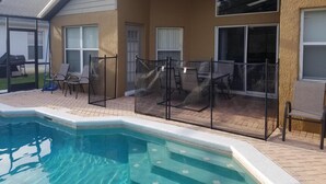 A poolside area with a covered patio, outdoor seating, and a view of the backyard. - 8054 Hidden Gem (Kissimmee)