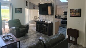 A spacious living area with a fireplace, leather sofas, a dining table, and a kitchen in the background. - 8054 Hidden Gem (Kissimmee)