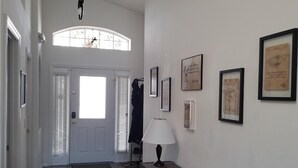 A hallway with a door, a lamp, and framed pictures on the wall. - 8054 Hidden Gem (Kissimmee)