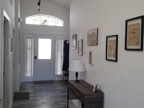 A hallway with a door, a lamp, and framed pictures on the wall.