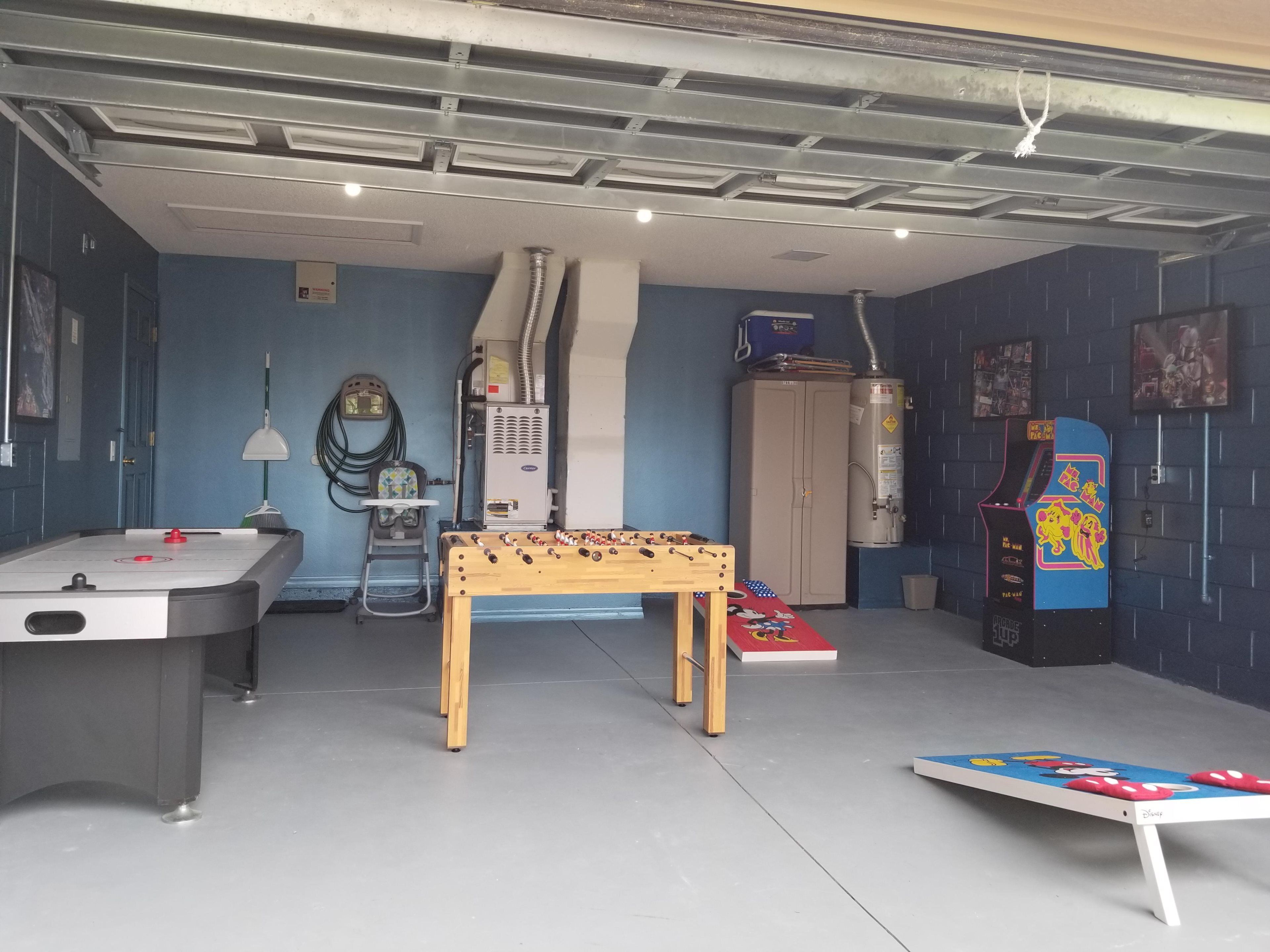 Una habitació amb taula de futbolí, taula de bitlles, una taula petita amb un llibre, un calefactor i un dispensador d'aigua.