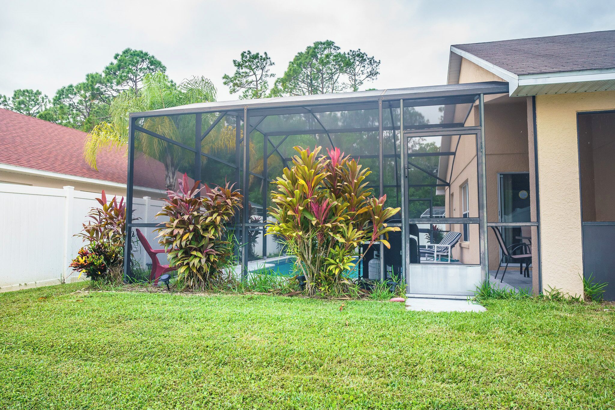A modern house with a glass-enclosed patio, a well-maintained lawn, and various potted plants.
