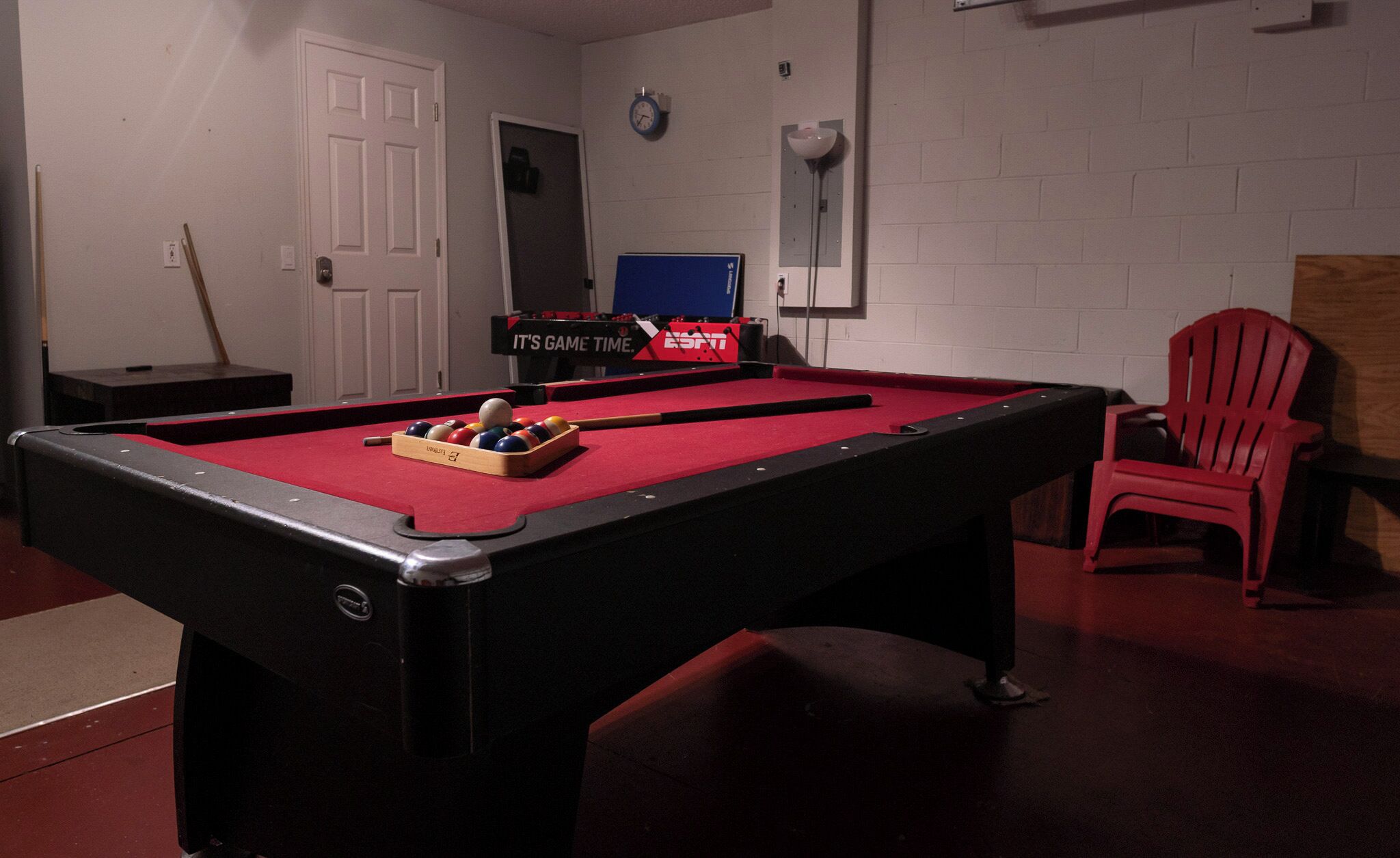 A pool table with balls, a clock, and a sign that says "IT'S GAME TIME."