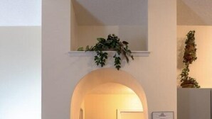 A living room with a brown sofa, a lamp, and a kitchen area with a counter and a hanging plant. - 4 Bed Villa - Eagle Pointe - Kissimmee (Kissimmee)