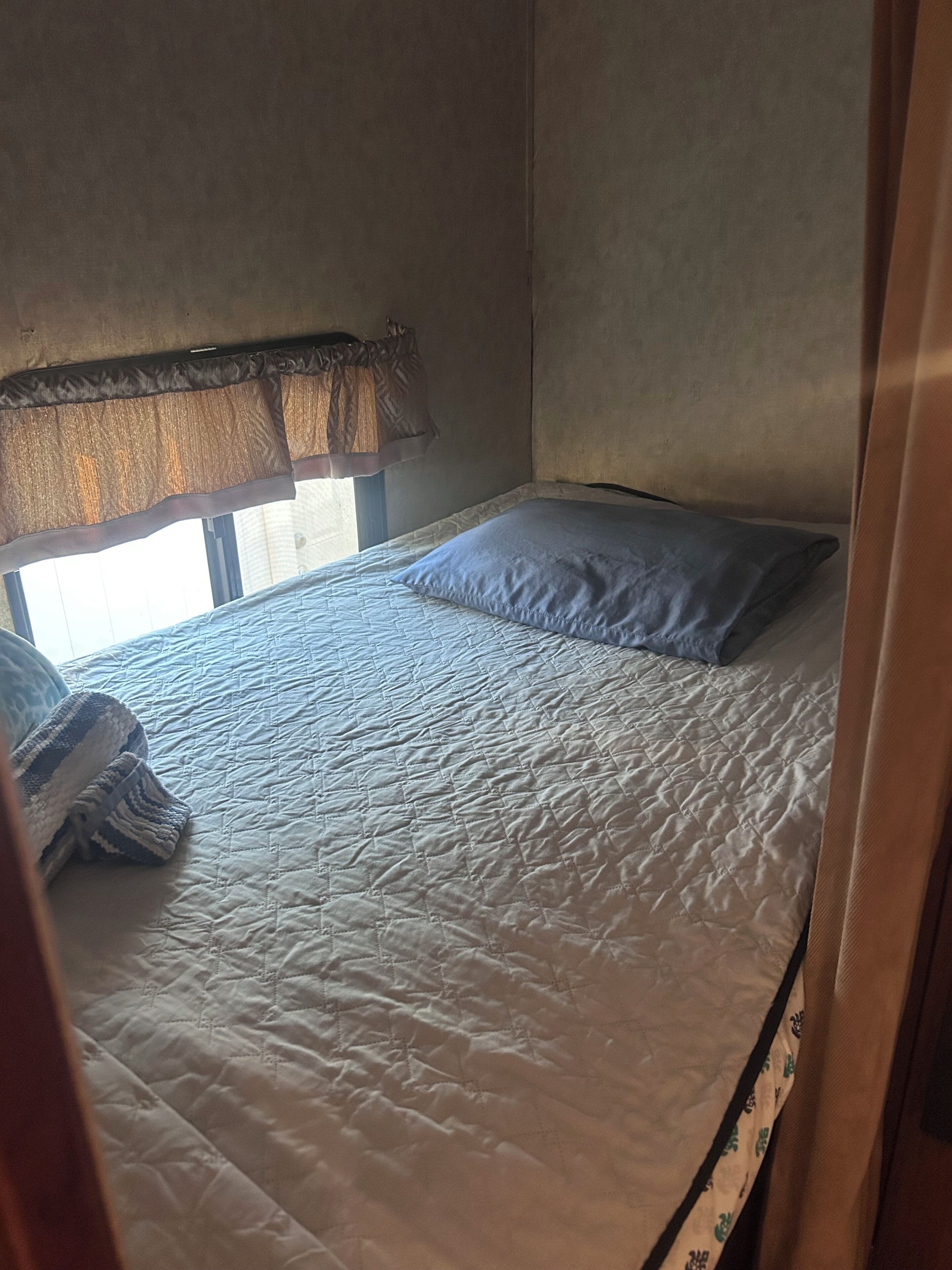 A single bed with a quilted mattress, a pillow, and a blanket.