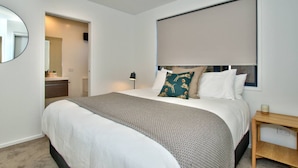 A modern hotel room with a large bed, a bedside table, a lamp, and a mirror. - Peaceful, Luxury Unit At The Iconic Remarkables! (Queenstown)